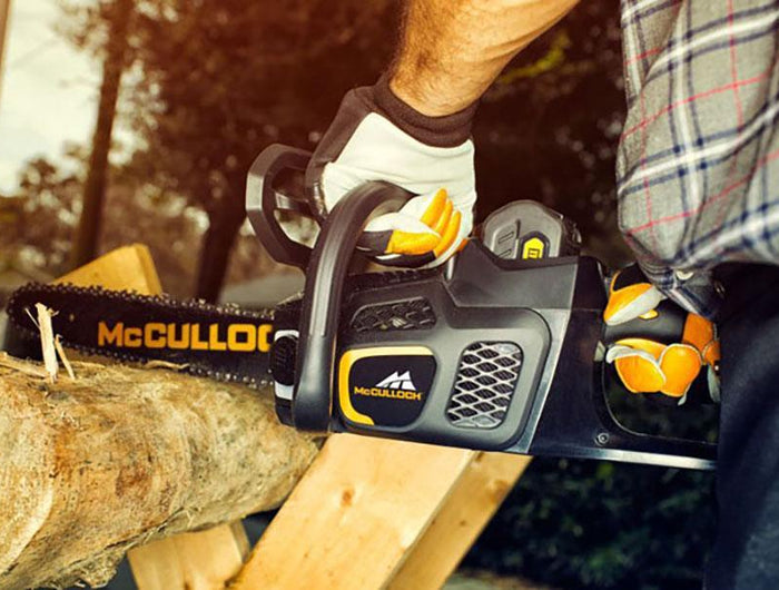 McCulloch chainsaw being used to cut through a log propped up on a wooden stand